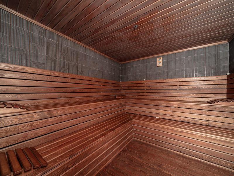 Interior de sauna de madera con bancos de varios niveles y paredes oscuras.