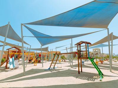 Un parco giochi con scivoli e altalene sotto diverse vele parasole in una giornata serena.