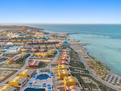 Vista aerea di un resort con piscine, edifici colorati e vista sul mare.