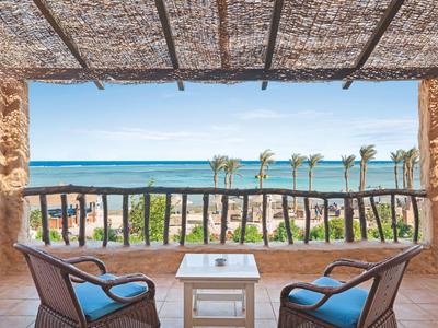 Terrasse avec vue sur la mer et fauteuils confortables sous un toit en treillis.