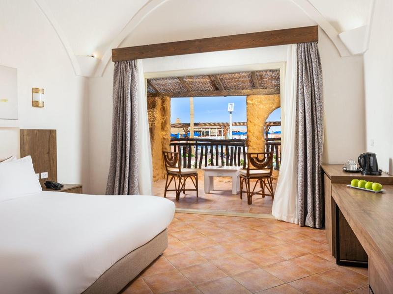 Chambre d'hôtel lumineuse avec lit double et terrasse donnant sur la mer.