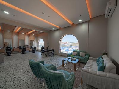 Amplia sala de estar del hotel con grupos de asientos, grandes ventanas y vista a la ciudad a la luz del día.