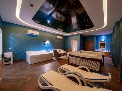 Habitación de spa elegante con bañera exterior, tumbonas y techo con estrellas.