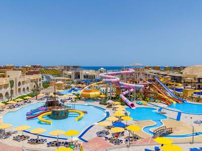 Groot waterpark met zwembaden, glijbanen en parasols onder een heldere lucht