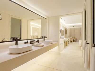 Salle de bain d'hôtel moderne avec doubles vasques et grand miroir, lumineuse et spacieuse.