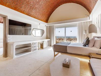 Hotelkamer met ronde plafond, tweepersoonsbed, zithoek en groot raam met uitzicht.