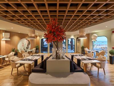 Ristorante moderno con pavimenti in legno, tavoli elegantemente apparecchiati e un grande centrotavola floreale al centro.