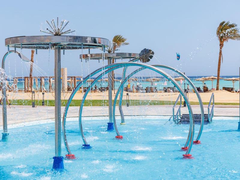 Zewnętrzny plac zabaw wodny z łukami i zraszaczami przy piaszczystej plaży