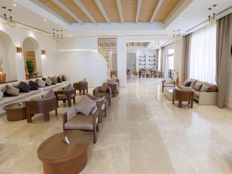 Ampio atrio dell'hotel con posti a sedere, dettagli in legno sul soffitto e grandi finestre per la luce naturale.