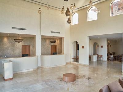 Spacious hotel lobby with marble floors, large arched windows, and modern lighting fixtures.