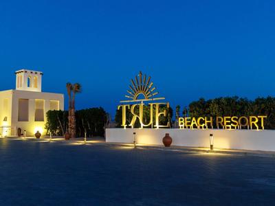 Illuminated entrance of a beach resort at dusk with clear blue sky.