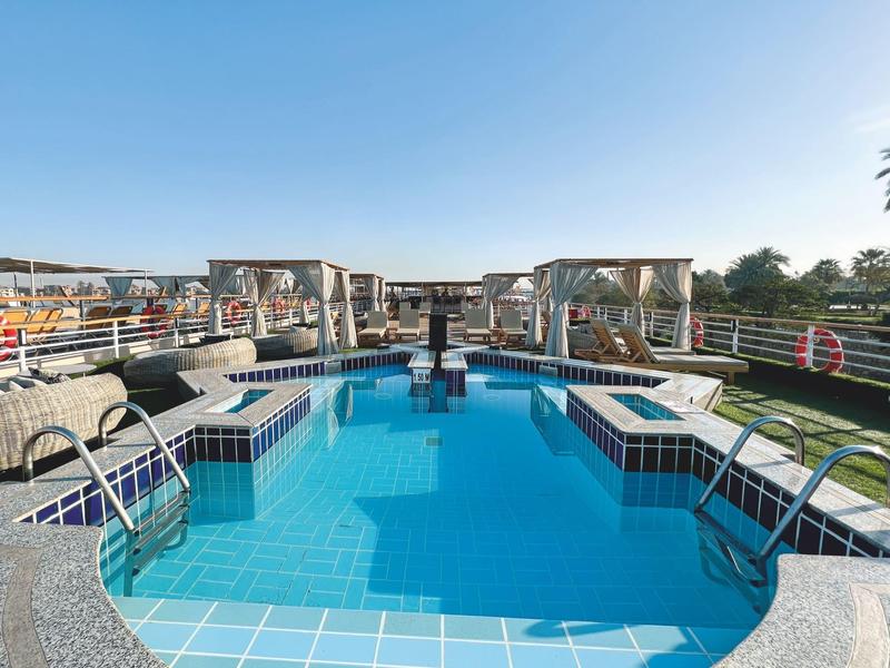 Modern buitenzwembad met helderblauw water en loungegebieden onder paviljoens.