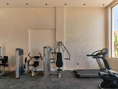 Gimnasio luminoso con máquinas modernas y ventana grande con vista al exterior.