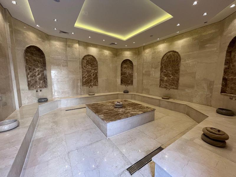 Luxurious spa room with warm light stone walls and built-in water feature.