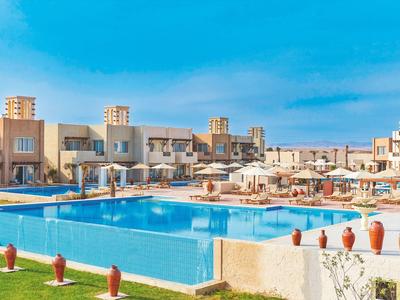 Grand bassin extérieur dans un hôtel moderne avec parasols et chaises longues.