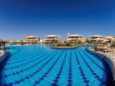 Large outdoor pool with clear blue water and sunny sky at a resort.