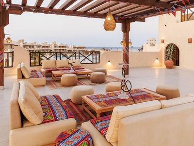 Terrazza coperta con comodi divani e tappeti decorativi dai colori caldi.