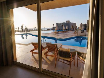 Vista de una piscina con tumbonas y arquitectura moderna al atardecer.