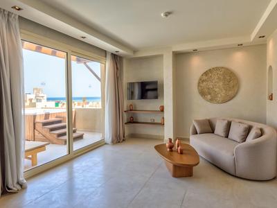 Moderne woonkamer met grote schuifdeuren naar terras en uitzicht op de oceaan.