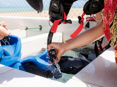 Personne remplissant un équipement de plongée d'eau sur un bateau, équipement suspendu à sécher.