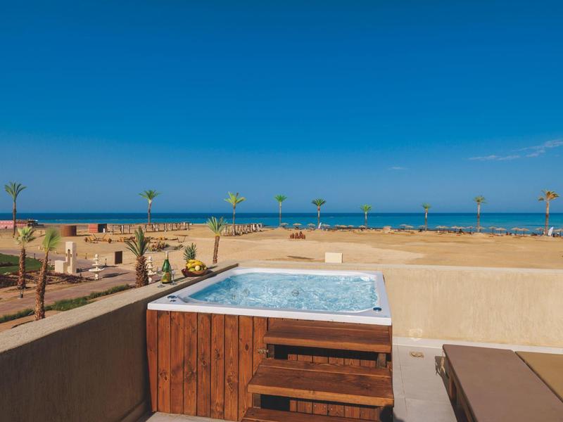 Vasca idromassaggio all'aperto su una terrazza con vista oceano sotto un cielo azzurro