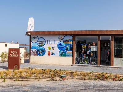 Un negozio di immersioni con murale colorata e attrezzatura subacquea sotto un cielo limpido.