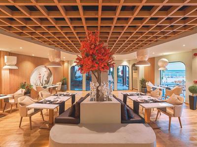 Elegant restaurant with wooden flooring, decorative red flowers, and large windows.