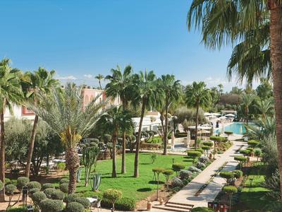 Luxuriöse Hotelanlage mit Palmen, gepflegtem Garten und Pool unter blauem Himmel