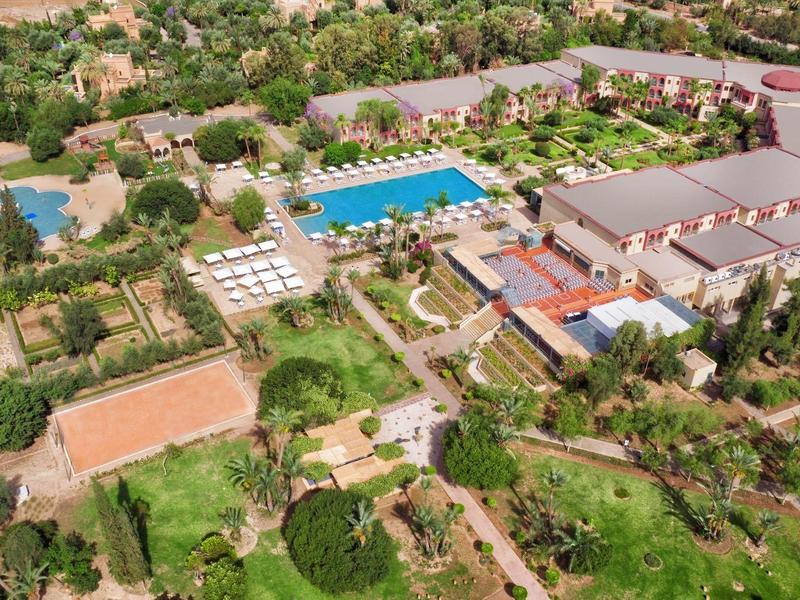 Letecký pohled na resort s velkými bazény, budovami a hojností zeleně.