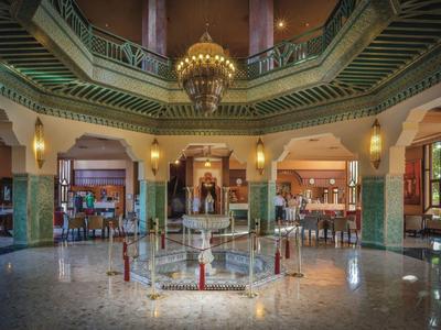 Spacious hotel lobby with central fountain, chandelier, and elegant green architecture.