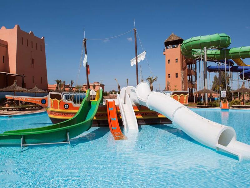 Toboggan aquatique et piscine dans un parc aquatique ensoleillé d'un complexe.