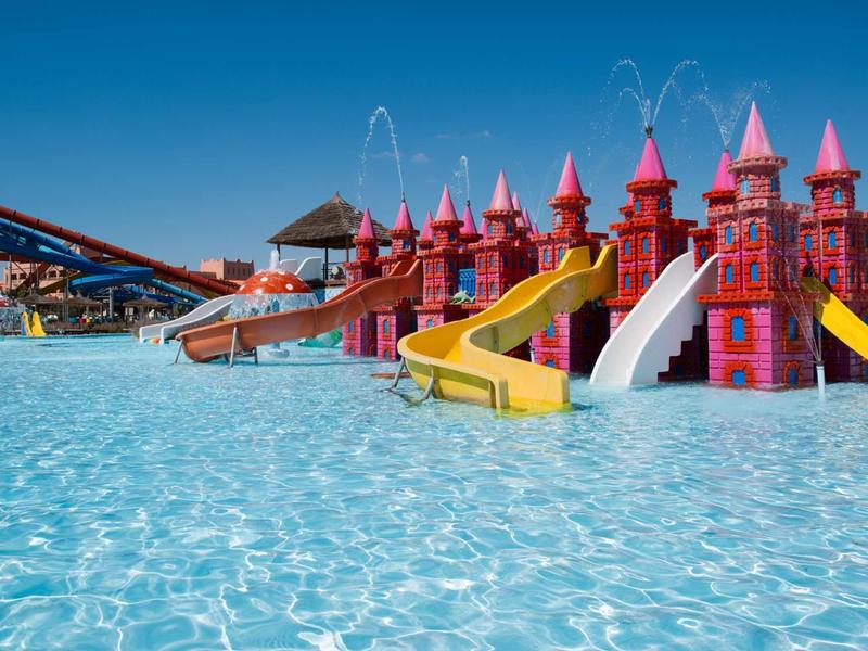 Parc aquatique coloré avec eau bleue claire et plusieurs toboggans.