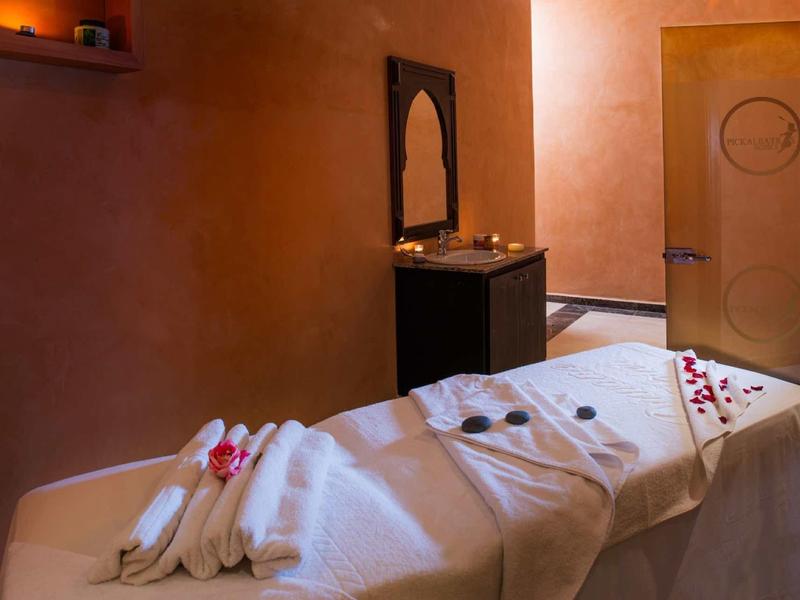 Salle de massage confortable aux couleurs chaudes, table de massage et ambiance relaxante.