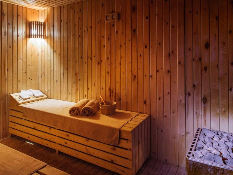 Sauna en bois avec table de massage, serviettes et lumière chaude sur le mur.
