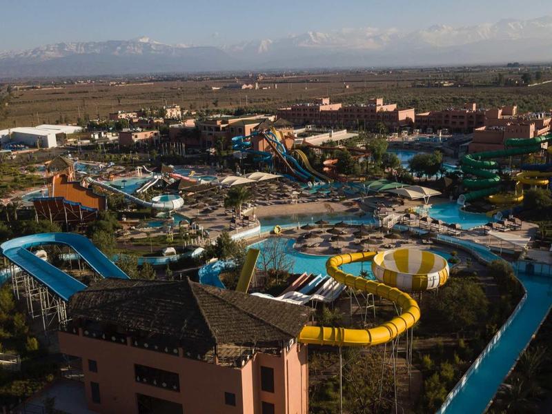 Grand parc aquatique avec plusieurs toboggans et piscines dans une station de vacances.