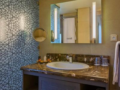 Moderní koupelna s mramorovou deskou, zrcadlem a světle modrými dekorativními dlaždicemi.