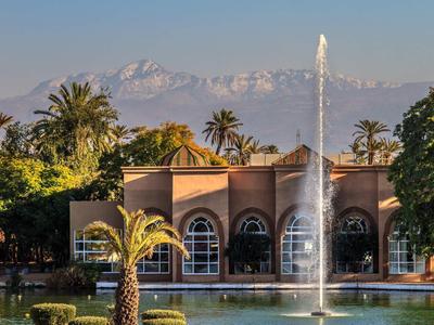 Gebäude mit Bogenfenstern vor Bergen und Springbrunnen im Wasserbecken