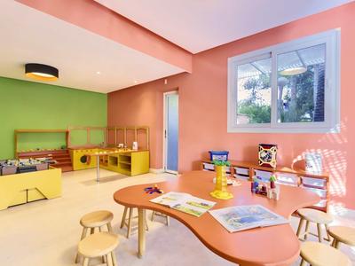 Barevná herna s živými stoly, stoličkami a hračkami v jasné místnosti.