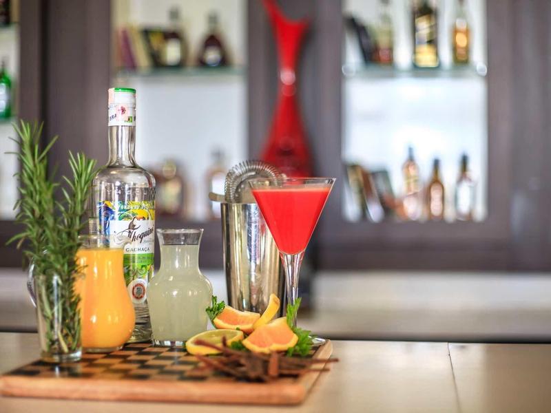 Barevné koktejly a čerstvé bylinky na dřevěné desce v hotelovém baru.