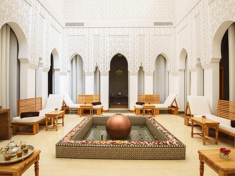 Světlé nádvoří s arabským designem, centrální fontánou a sezením v hotelu.