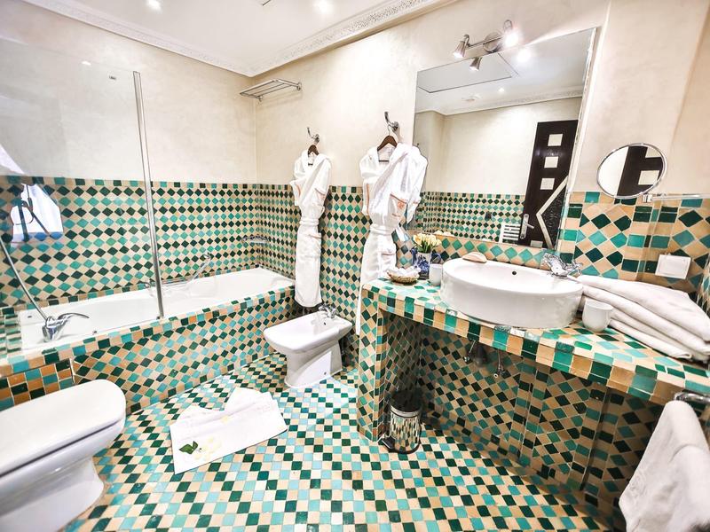 Bagno moderno con piastrelle colorate, vasca, lavabo e asciugamani.