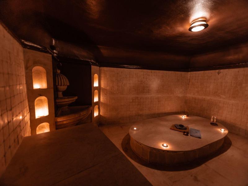 Stanza wellness calda e soffusa con vasca idromassaggio rotonda e illuminazione ambientale.