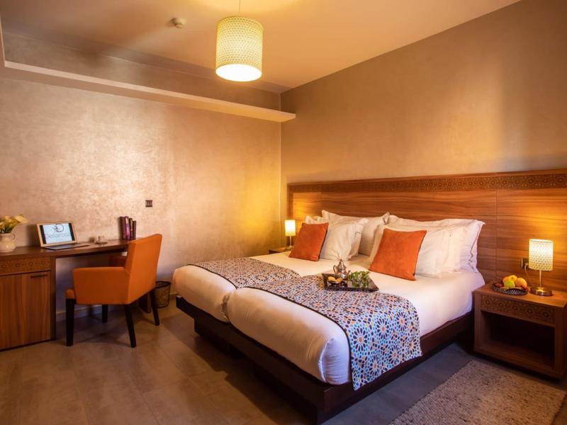 Camera d'hotel accogliente con letto matrimoniale, scrivania e illuminazione calda.