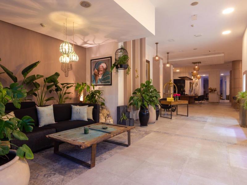 Elegante hall dell'hotel con area salotto, piante e illuminazione moderna.