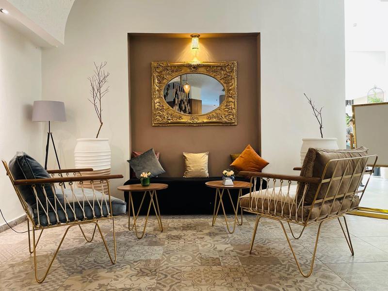 Area salotto moderna con due sedie, divano e parete illuminata caldamente