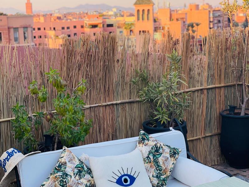 Accogliente terrazza con mobili bianchi, cuscini e vista sulla città al tramonto.