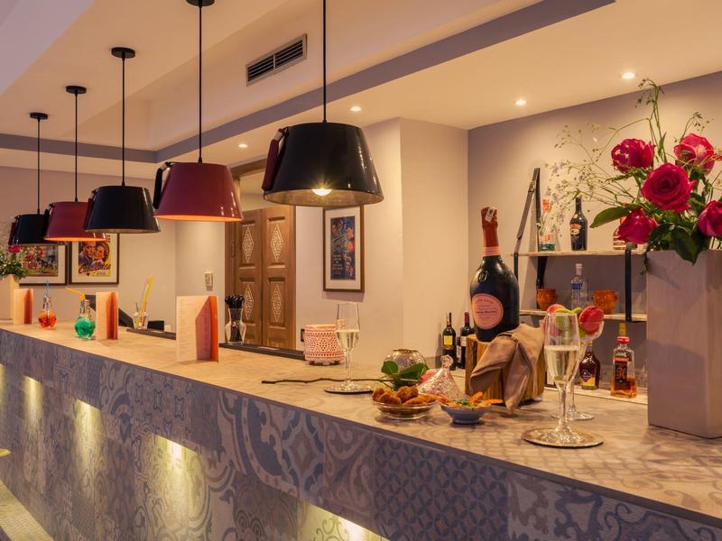 Banco reception moderno dell'hotel illuminato con lampade sospese e composizione floreale.