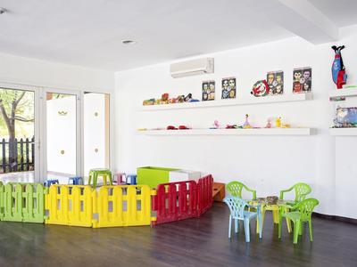 Children's play area with colorful fence and chairs in a bright room with large windows.