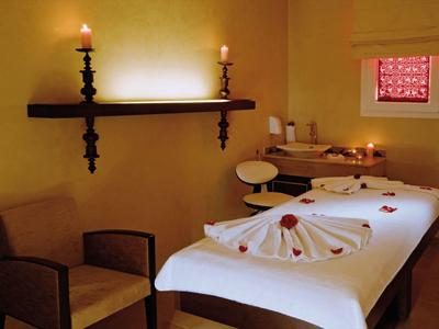 A relaxing massage room with a massage table, candles, and a comfortable chair.