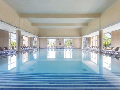 Large, bright indoor swimming pool with loungers in a modern setting.